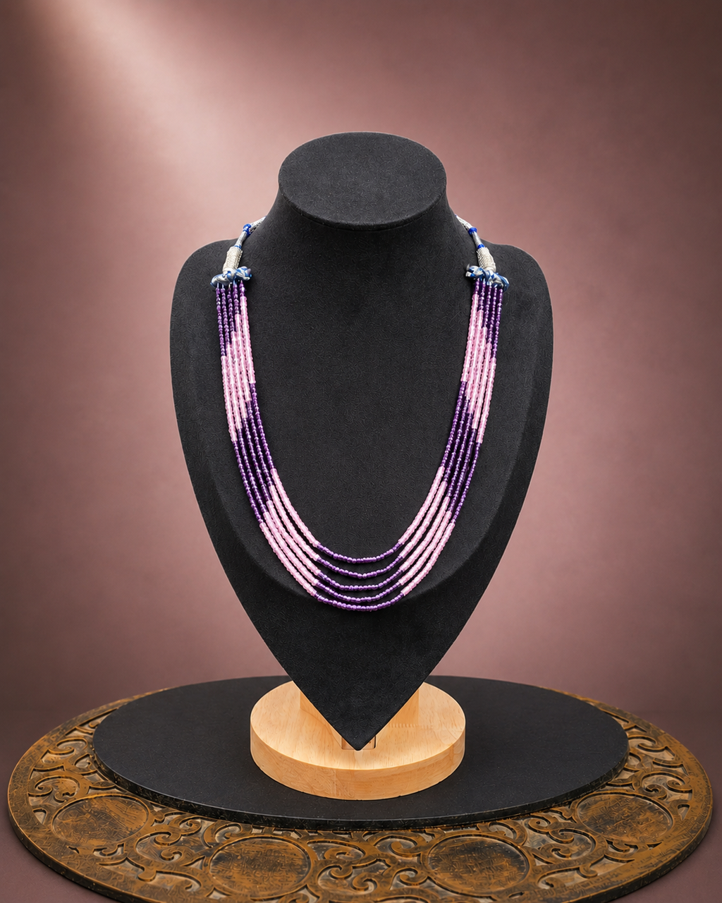Blush and plum multi-strand beaded necklace displayed on a dark jewellery bust