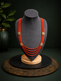 Coral red multi-strand floral beaded necklace front view on a dark jewellery bust