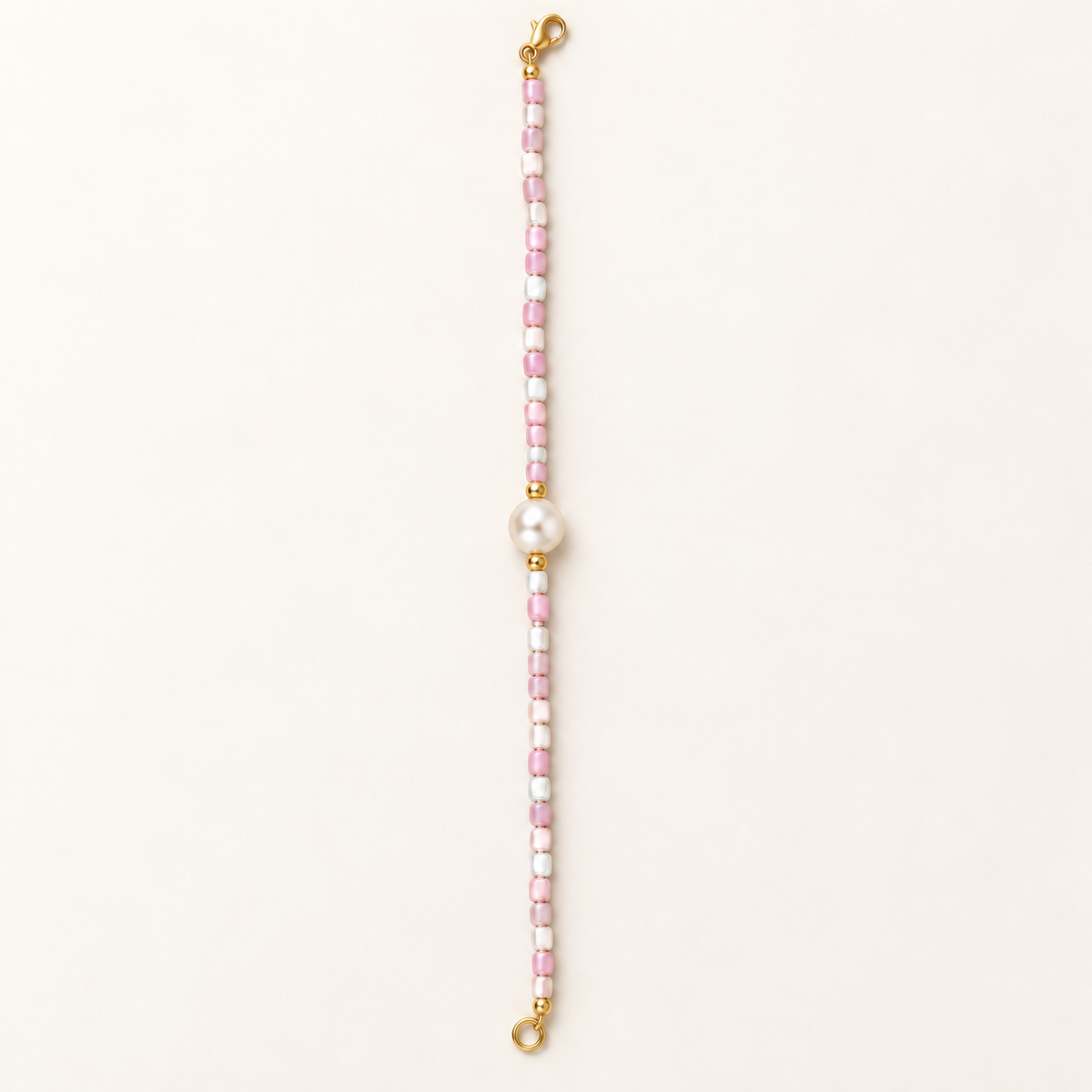 Blush pink and white beaded bracelet with central pearl-style accent and gold-tone details – full product view
