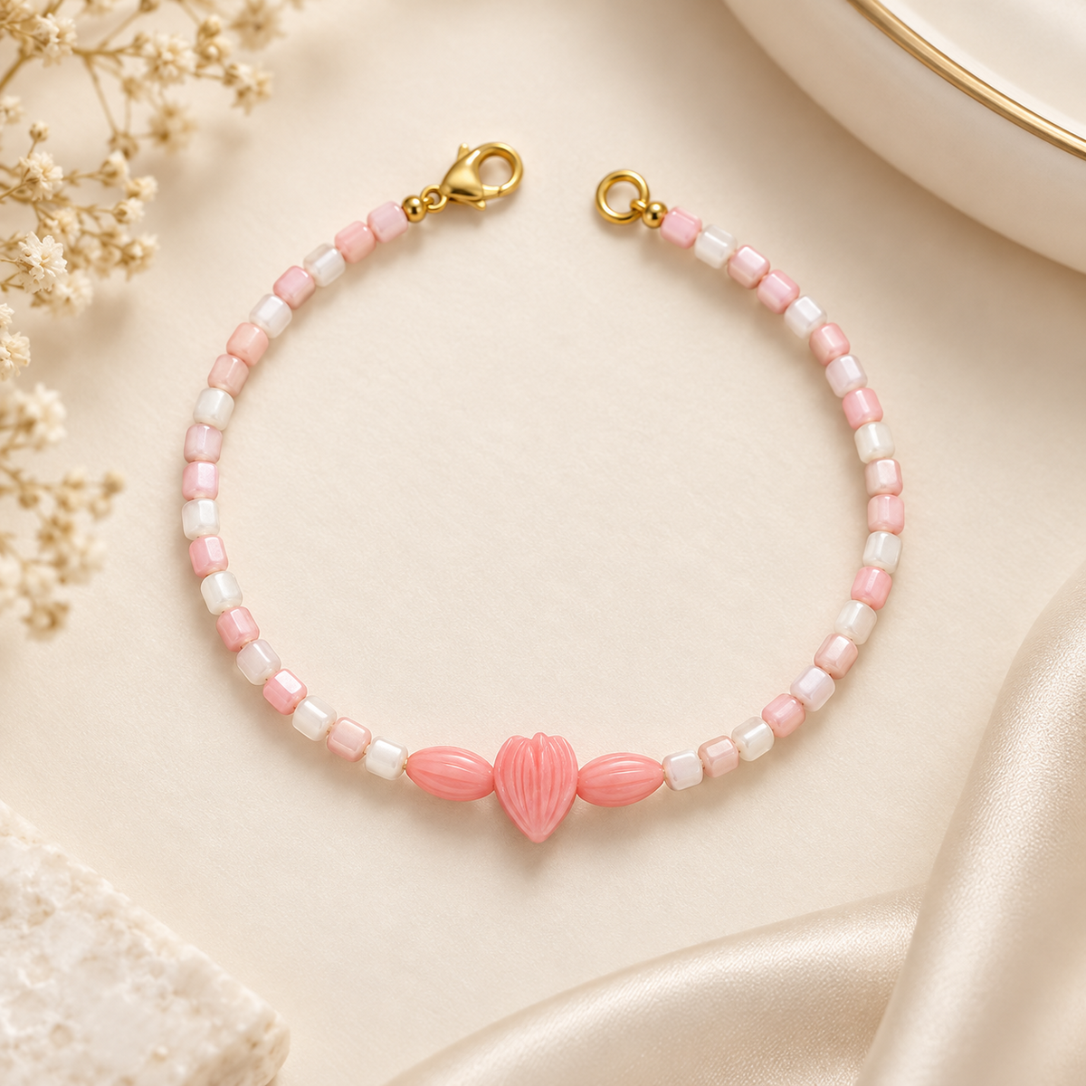 Blush pink and ivory beaded bracelet with three carved pink centre beads – detailed flat lay