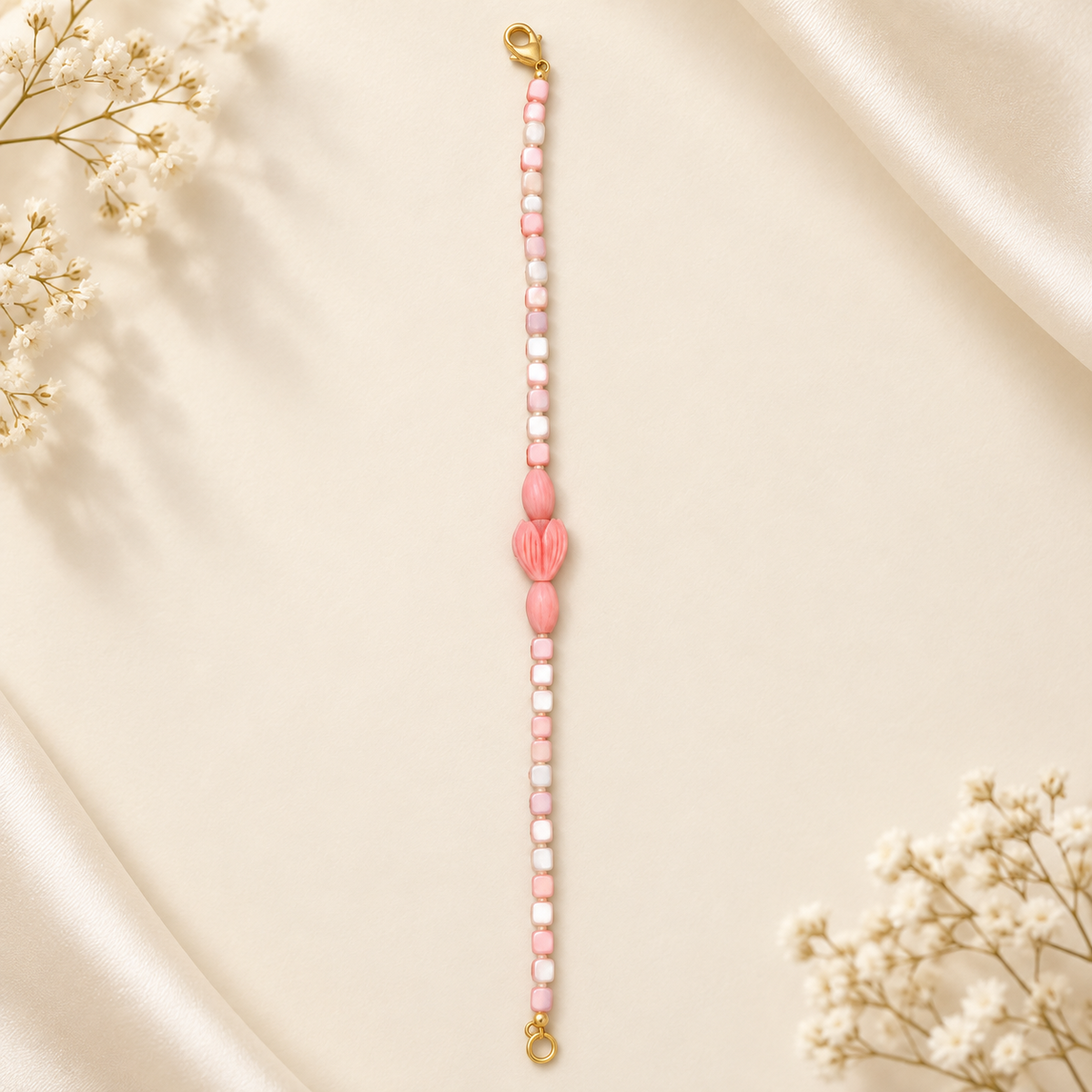 Blush pink and ivory beaded bracelet with carved floral centre and gold-tone lobster clasp – flat lay
