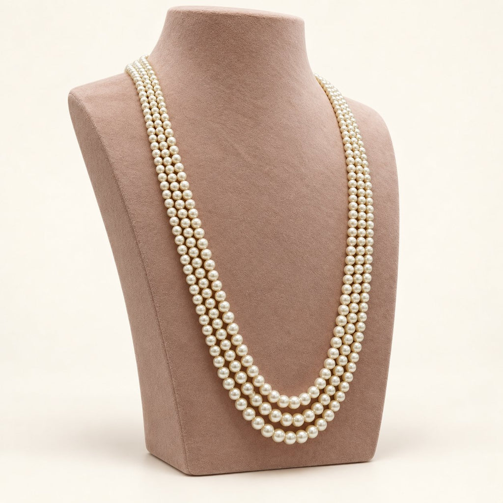 Cream triple-strand pearl-style necklace on a taupe bust – left view