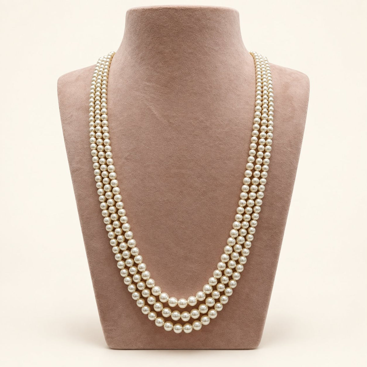 Cream triple-strand pearl-style necklace on a taupe bust – main view