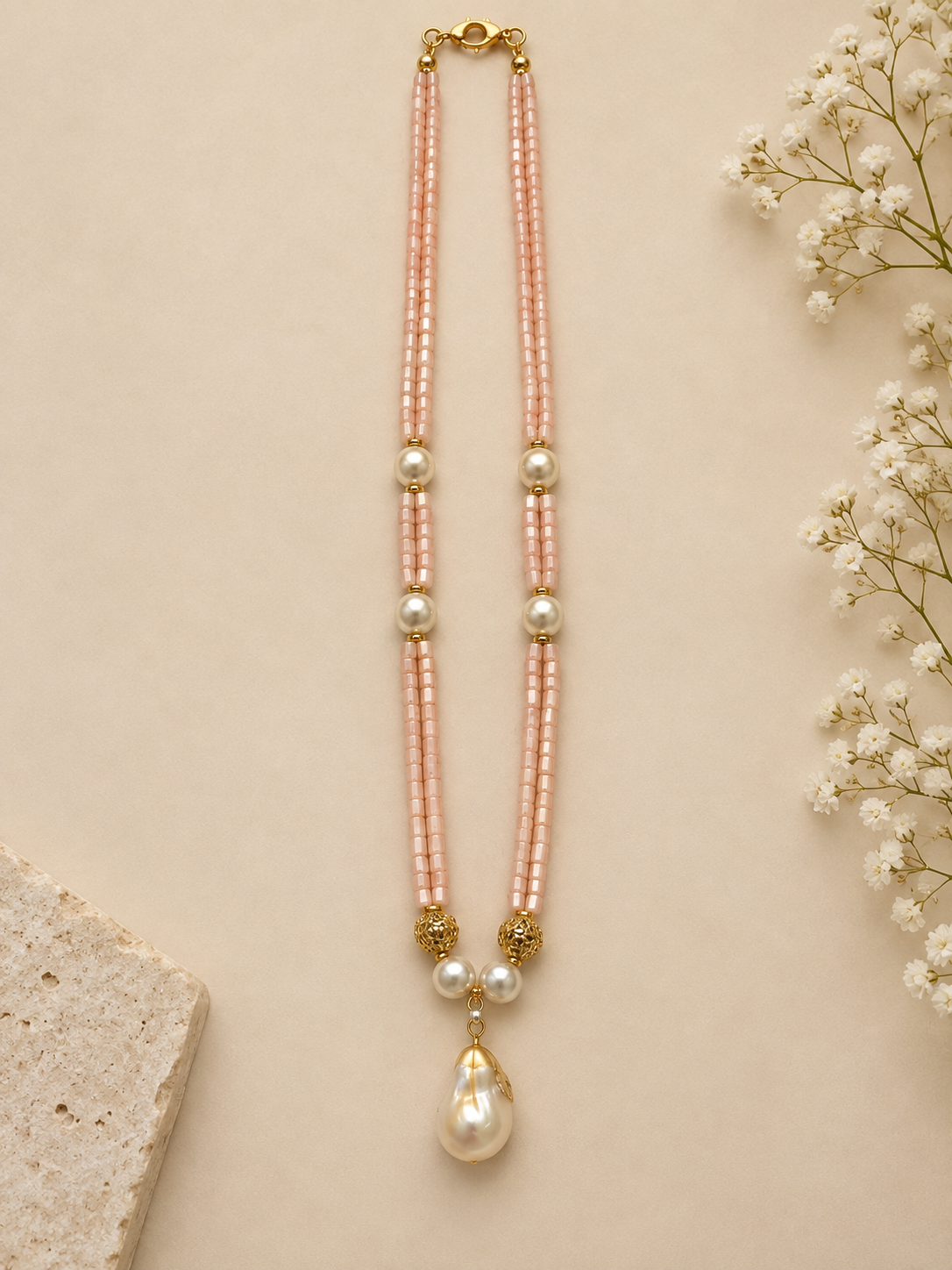 Pink double-strand beaded necklace with pearl-style teardrop pendant – full-length flat lay