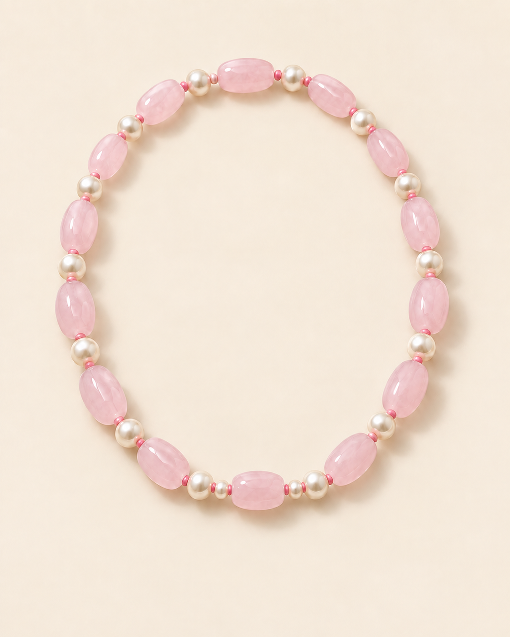 Blush pink oval beaded necklace with ivory accents and two small beads beside the centre bead – flat lay view