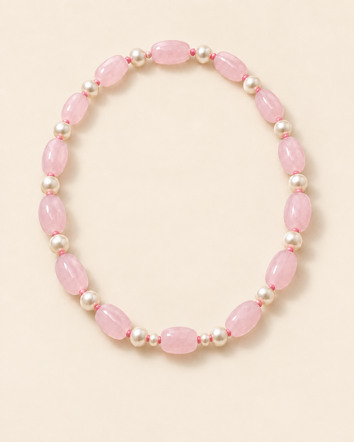 Blush pink oval beaded necklace with ivory accents and two small beads beside the centre bead – flat lay view